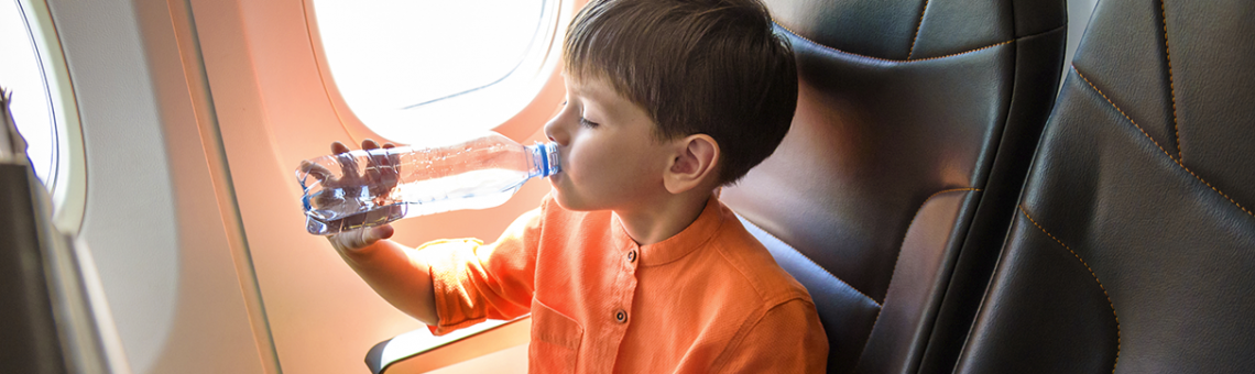 Image of a boy drinking water from a bottle on the plane.