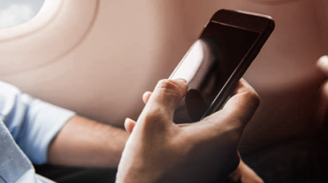 Passageiro segurando celular na mão dentro do avião